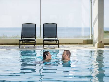 A man and woman are swimming in the swimming pool of Landal Strandappartementen Fyrklit