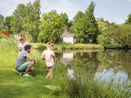 A family is fishing in the water of holiday park Landal De Bloemert