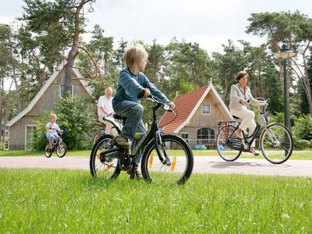 Family cycle past holiday homes at Landal De Hellendoornse Berg holiday park
