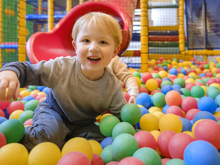Child plays in the ball pit of the indoor playground at Landal De Hellendoornse Berg holiday park