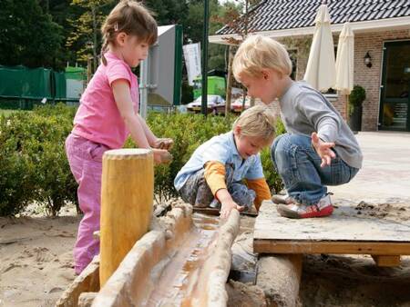 Children play with water in the playground of holiday park Landal De Hellendoornse Berg