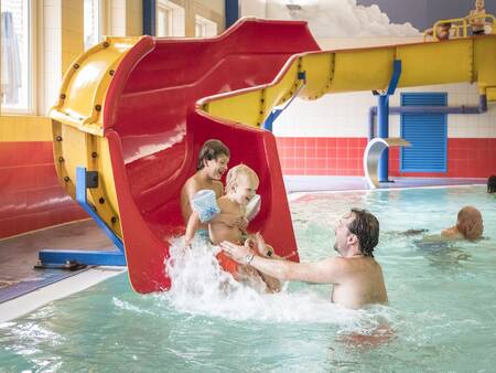 Children slide down the slide in the swimming pool of the Landal De Hellendoornse Berg holiday park