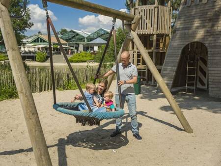 Swing with climbing equipment in a playground at holiday park Landal De Lommerbergen