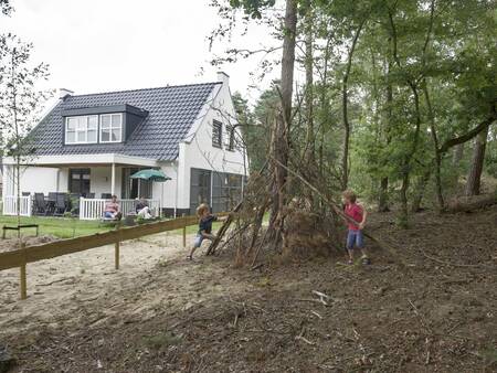 Children build a hut in the woods next to a holiday home at the Landal De Vers holiday park