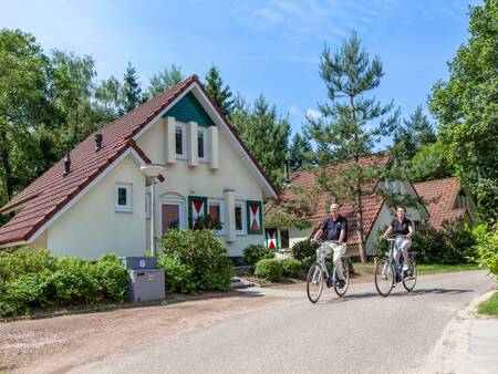 Man and woman cycling in front of a few holiday homes at Landal De Vers holiday park