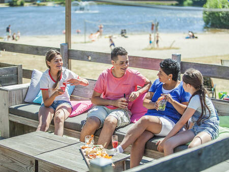 Family on a terrace by the natural pool at the Landal Domein de Schatberg holiday park