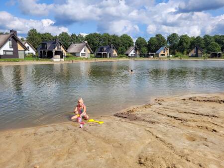 Girl plays on the beach at a holiday home on the water at Landal Drentse Lagune