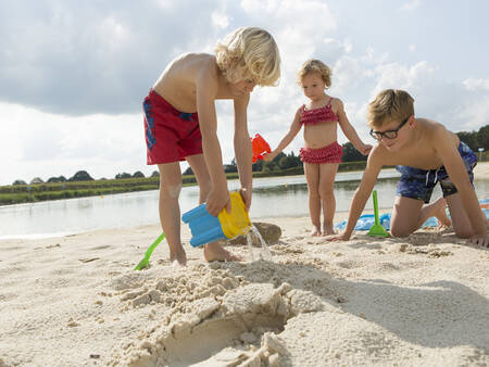 Children play on the beach of the recreational lake of holiday park Landal Dwergter Sand