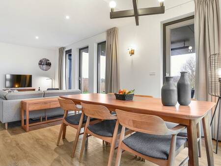 Dining table and living room of a holiday home at Landal Elfstedenhart holiday park