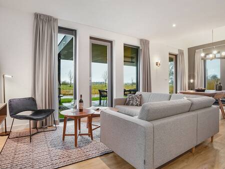 Living room with large windows of a holiday home at Landal Elfstedenhart holiday park