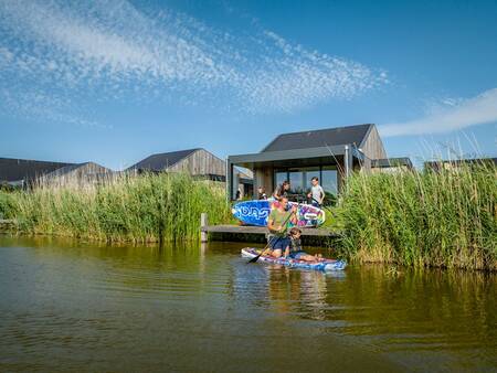 Family with sup boards on a jetty at a holiday home at Landal Elfstedenhart holiday park