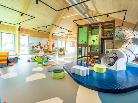 Child slides down the slide in the indoor playground at Landal Elfstedenhart holiday park