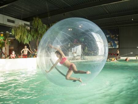 Girl in a big ball in the swimming pool of the Landal Esonstad holiday park