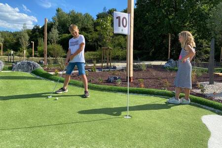 Children playing golf on the mini golf course at the Landal Forest Resort Your Nature holiday park