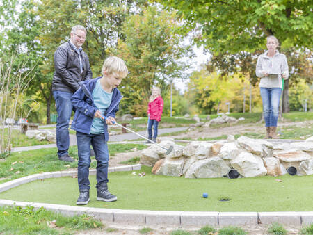 A family plays golf on the miniature golf course of the Landal Hochwald holiday park