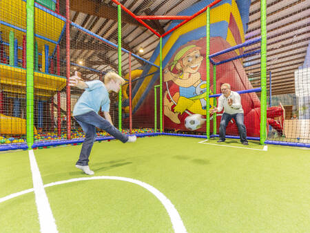Father and son play football in the indoor play paradise of the Landal Hochwald holiday park