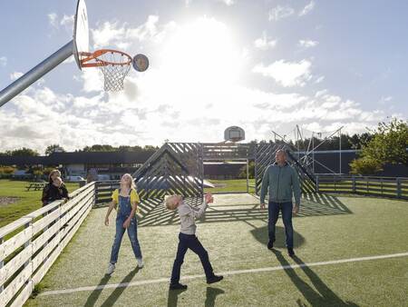 Family plays a game of basketball on the playing field of Landal Vakantiepark Søhøjlandet