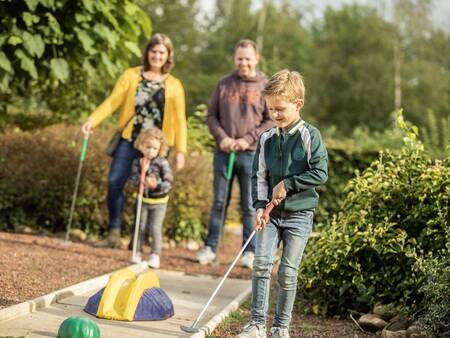 Family plays golf on the miniature golf course of the Landal Hunerwold State holiday park