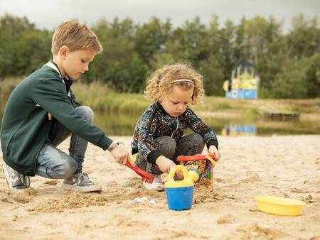 Children play on the beach of the recreational lake of the Landal Hunerwold State holiday park