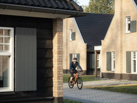 Man cycling between holiday homes at Landal Kaatsheuvel holiday park
