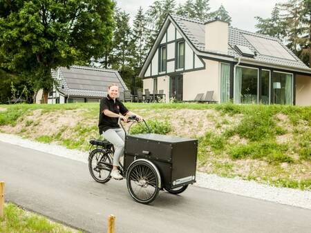 Woman with cargo bike in front of holiday homes at Landal Mont Royal holiday park