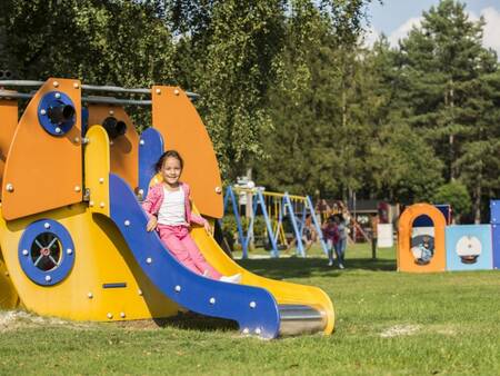 Child slides down a slide in a playground at holiday park Landal Mooi Zutendaal