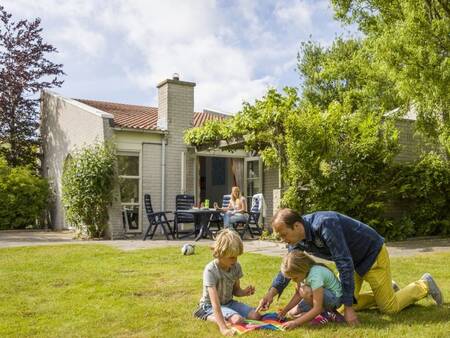 Family plays in the garden of a holiday home at the Landal Port Greve holiday park