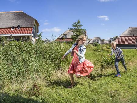 Children play on the grass at holiday homes in the Landal Sluftervallei vakantie holiday park