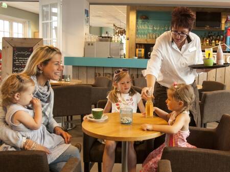 A family enjoys a drink at Restaurant De Smokkelaar at Landal Strand Resort Nieuwvliet-Bad