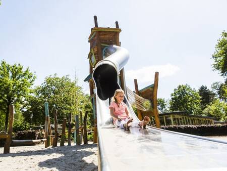 Child slides down the slide in a playground at Landal Twenhaarsveld holiday park