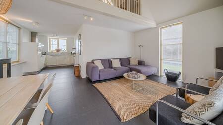 Living room with sofas dining table and kitchen of a holiday home at Landal Vakantiepark Duynvallei