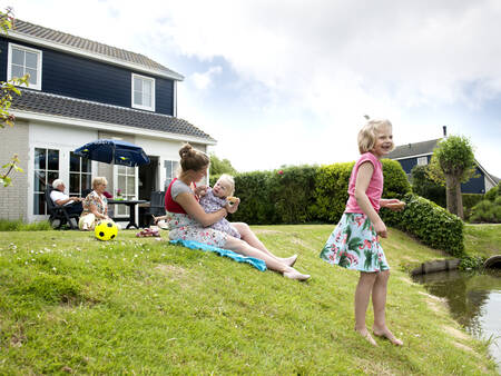 Family in the garden of a villa on the water at holiday park Landal Villapark Livingstone