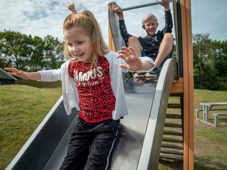 Children slide down a slide in a playground at Landal Vitamaris