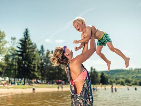 Woman with child on the recreational beach of holiday park Landal Waterpark Marina Lipno