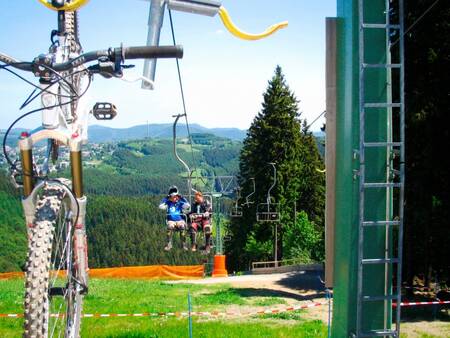 Landal Winterberg - 2 people and a mountain bike in a chairlift