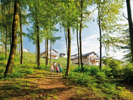 Family walks between trees with Landal Winterberg holiday homes in the background