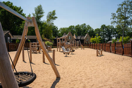 Outdoor playground with wooden play equipment at the holiday park Landgoed De IJsvogel