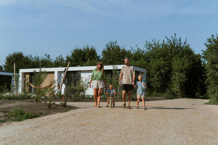 Family walking on a path near a holiday home at the MarinaPark Residentie Bloemendaal holiday park