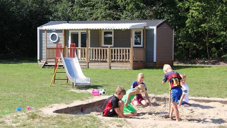 A small playground between chalets on a field at holiday park Molecaten Bosbad Hoeven