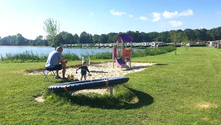 Father with child in a small playground at holiday park Molecaten Park De Agnietenberg