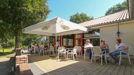 People on the terrace at the restaurant and snack bar at holiday park Molecaten Park De Koerberg
