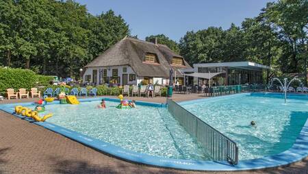 People swim in the outdoor pool of holiday park Molecaten Park De Leemkule