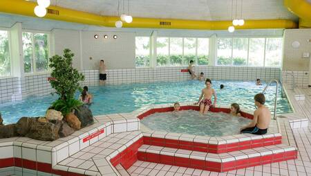 People swim in the indoor pool with bubble bath of holiday park Molecaten Park De Leemkule