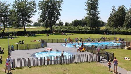 People in the outdoor pool with sunbathing area at holiday park Molecaten Park Flevostrand