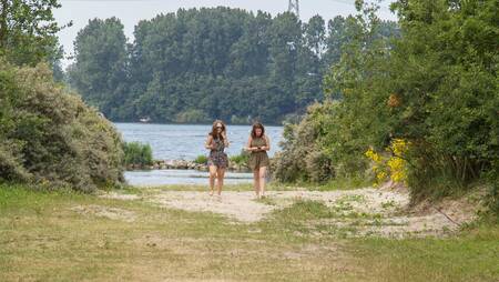Two women walk near the Brielse Meer at holiday park Molecaten Park Kruininger Gors