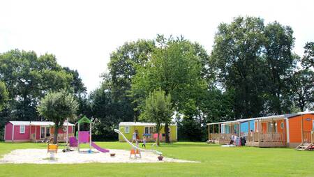 Chalets on a field with a playground at holiday park Molecaten Park Kuierpad