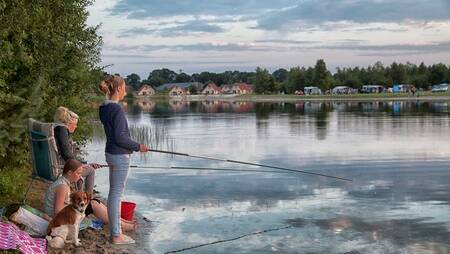Children fishing in the lake at holiday park Molecaten Park Kuierpad