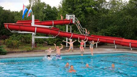 People swimming in the outdoor pool with slide at holiday park Molecaten Park Kuierpad