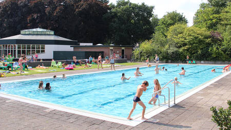 People swimming in the outdoor pool of holiday park Molecaten Park Landgoed Ginkelduin