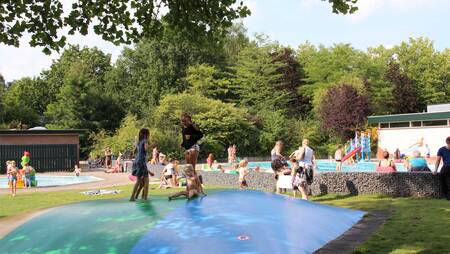 Children jump on the trampoline at the swimming pool of Molecaten Park Landgoed Ginkelduin